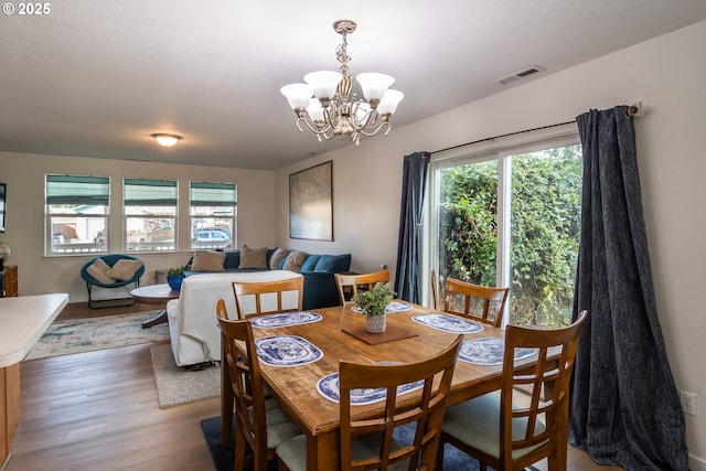 dining space with visible vents, a notable chandelier, and light wood-style flooring