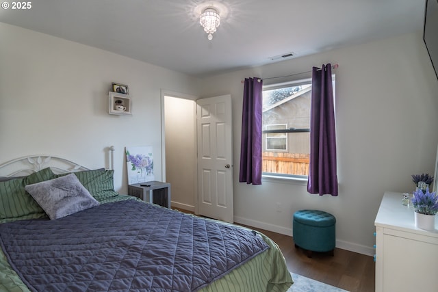 bedroom with multiple windows, wood finished floors, visible vents, and baseboards