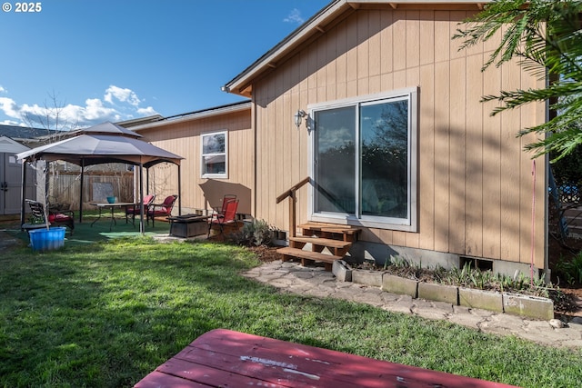 view of property exterior featuring a gazebo, a lawn, entry steps, and fence