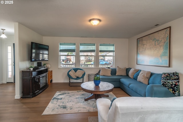 living area with visible vents and wood finished floors