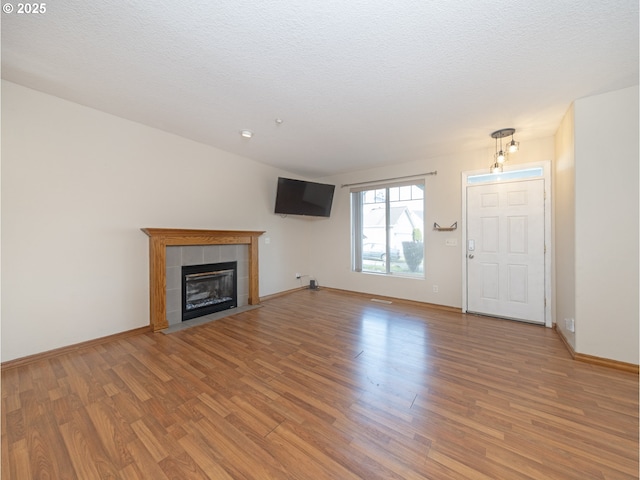 1616 Primrose Ln, Forest Grove, OR 97116 - unfurnished living room featuring light wood finished floors, a tiled fireplace, baseboards, and a textured ceiling