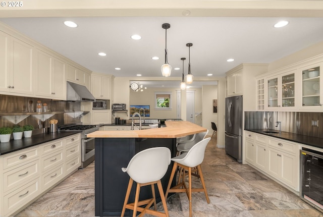 3184 SW 73rd Ave, Portland, OR 97225 - kitchen with beverage cooler, an island with sink, appliances with stainless steel finishes, butcher block counters, and recessed lighting