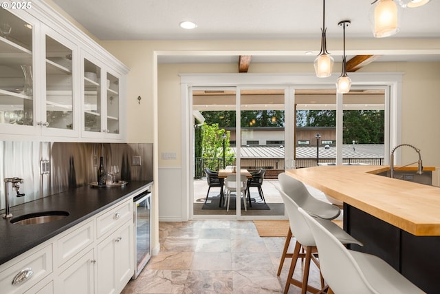 3184 SW 73rd Ave, Portland, OR 97225 - kitchen with pendant lighting, beverage cooler, glass insert cabinets, a sink, and white cabinetry
