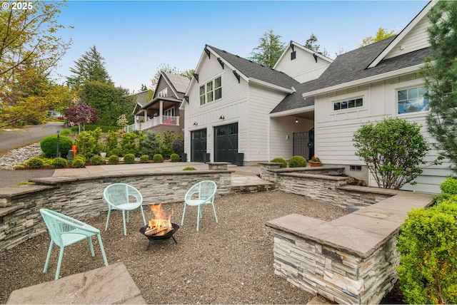 3184 SW 73rd Ave, Portland, OR 97225 - back of house featuring board and batten siding, roof with shingles, a fire pit, and a garage