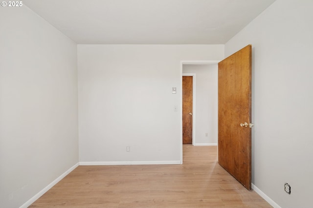 spare room featuring light wood-type flooring and baseboards