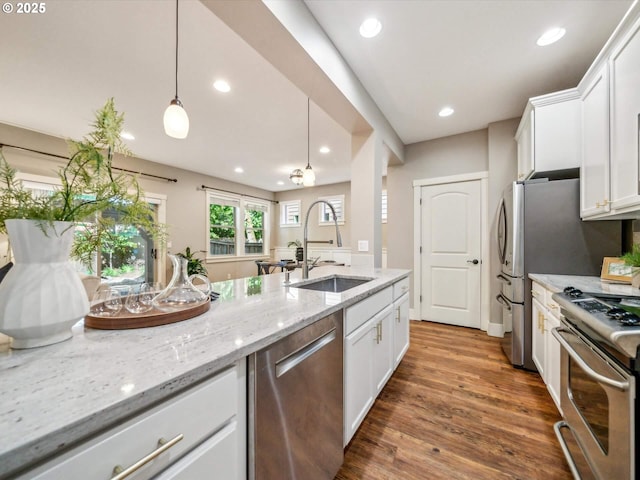 kitchen with a sink, white cabinetry, appliances with stainless steel finishes, and wood finished floors