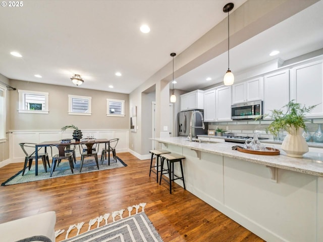 kitchen featuring decorative backsplash, a kitchen breakfast bar, stainless steel appliances, and wood finished floors