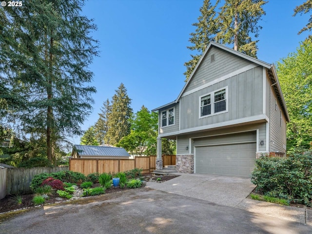 exterior space with board and batten siding, fence, concrete driveway, an attached garage, and stone siding