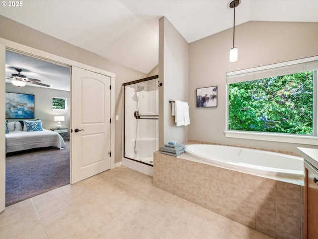 ensuite bathroom featuring tile patterned floors, vaulted ceiling, a stall shower, and a wealth of natural light