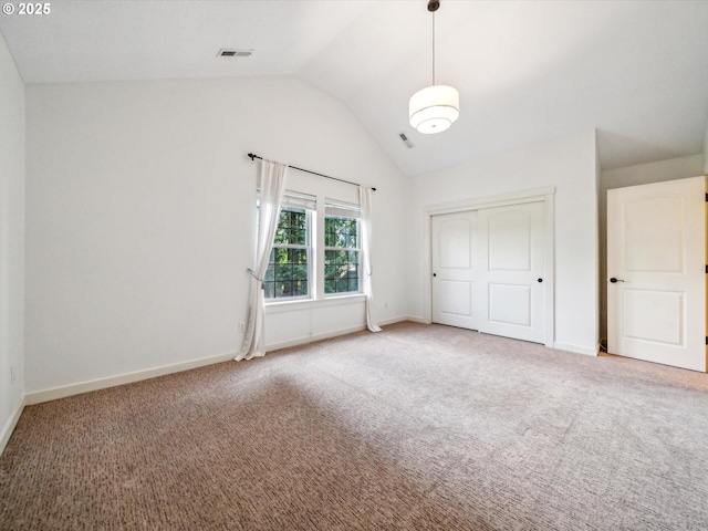 unfurnished bedroom with vaulted ceiling, a closet, carpet flooring, and visible vents