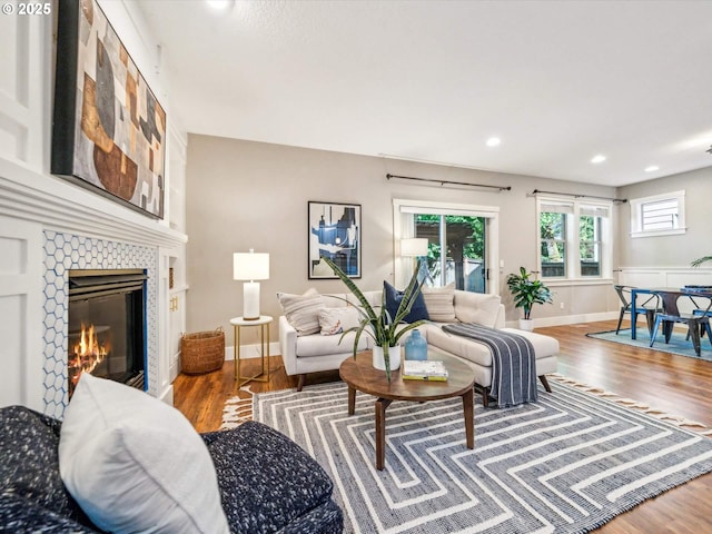 living room featuring baseboards, a fireplace, recessed lighting, and wood finished floors
