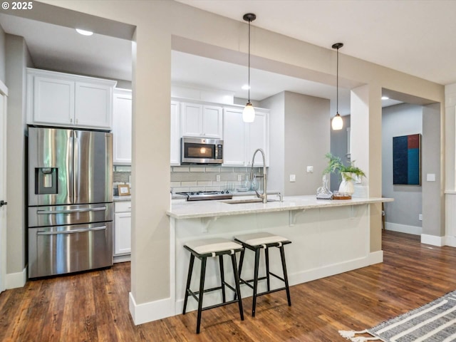 kitchen with a breakfast bar area, white cabinetry, tasteful backsplash, a sink, and appliances with stainless steel finishes