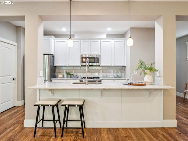 kitchen with baseboards, appliances with stainless steel finishes, backsplash, and white cabinets
