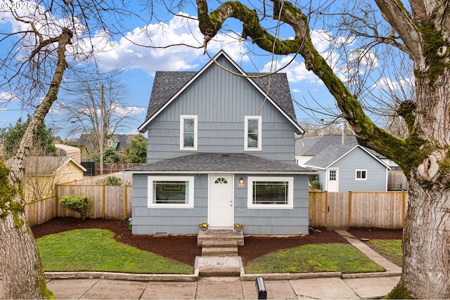 view of front facade with a shingled roof and fence private yard