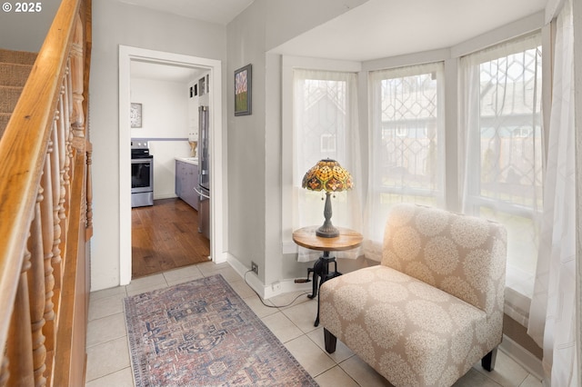 living area featuring stairs, light tile patterned flooring, and baseboards