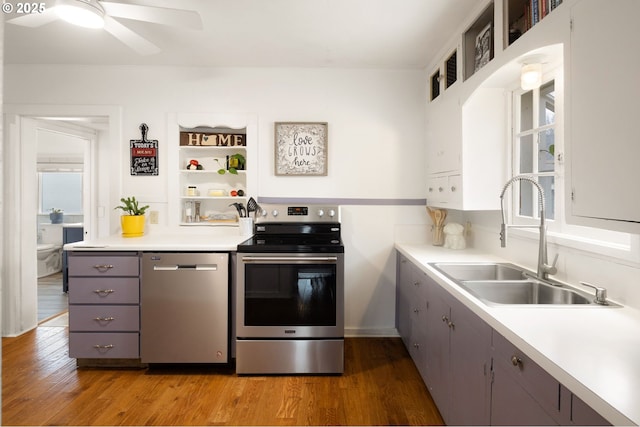 kitchen featuring light wood-style flooring, gray cabinetry, stainless steel appliances, a sink, and light countertops