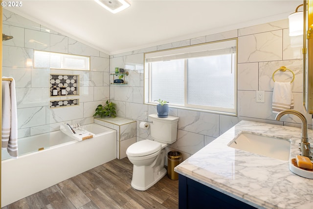 bathroom featuring lofted ceiling, toilet, wood finished floors, vanity, and tile walls