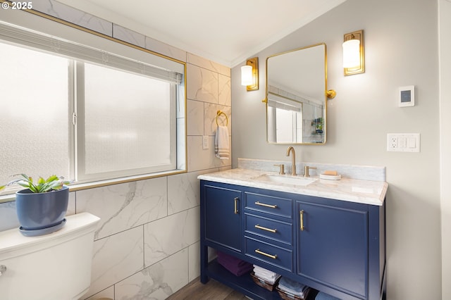 bathroom featuring toilet, tile walls, and vanity