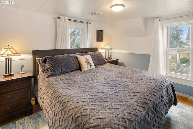 bedroom with baseboards, visible vents, and wood finished floors