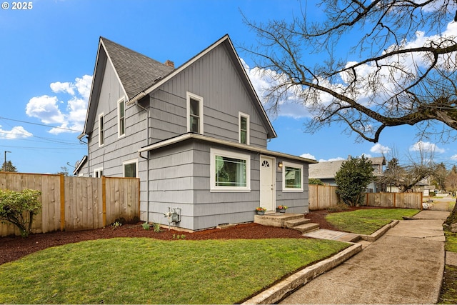 view of front of property featuring a shingled roof, a front yard, and fence