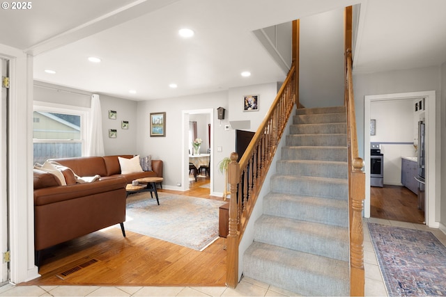 tiled living area featuring recessed lighting, visible vents, baseboards, and stairs