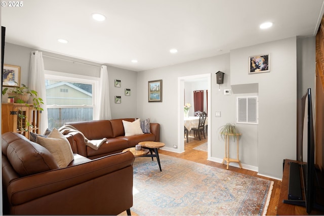 living room featuring baseboards, visible vents, wood finished floors, and recessed lighting