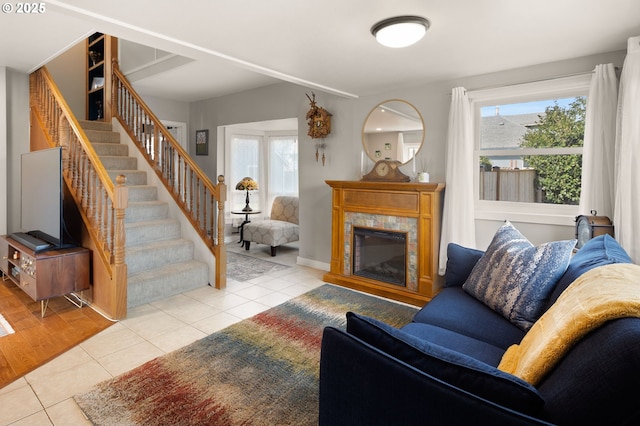 living room featuring tile patterned flooring, stairway, a wealth of natural light, and a tile fireplace