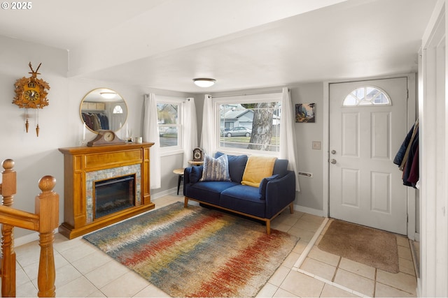 foyer entrance featuring light tile patterned floors, plenty of natural light, and a glass covered fireplace