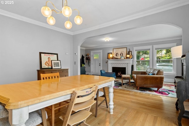 165 15th St, Salem, OR 97301 - dining space featuring arched walkways, a brick fireplace, light wood-style floors, ornamental molding, and a chandelier