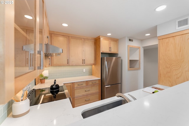 kitchen with a sink, freestanding refrigerator, visible vents, backsplash, and light countertops