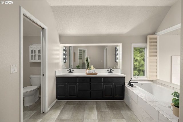 4025 Horton Rd, West Linn, OR 97068 - bathroom featuring wood finished floors, a bath, double vanity, and a textured ceiling