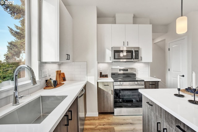 1669 SE Sherrett St, Portland, OR 97202 - kitchen featuring appliances with stainless steel finishes, light wood-style floors, tasteful backsplash, and light countertops