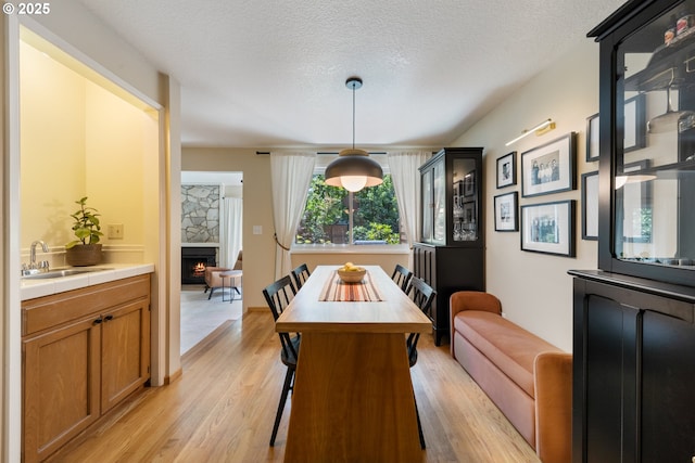 4300 Botticelli St, Lake Oswego, OR 97035 - dining area featuring a stone fireplace, light wood-style floors, and a textured ceiling