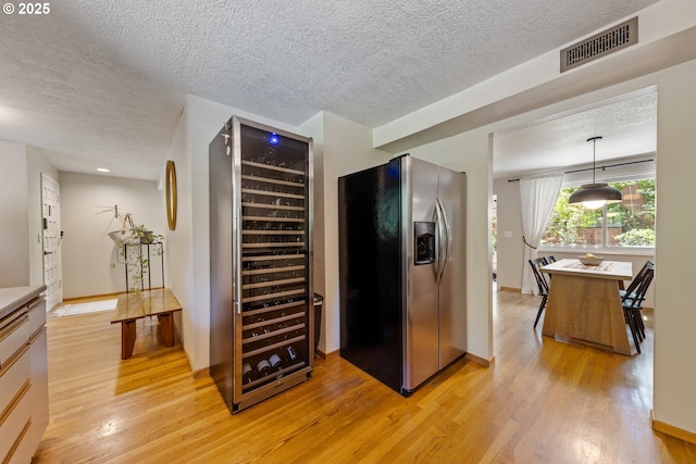 4300 Botticelli St, Lake Oswego, OR 97035 - kitchen featuring stainless steel fridge with ice dispenser, wine cooler, light wood-style flooring, a textured ceiling, and hanging light fixtures