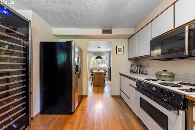4300 Botticelli St, Lake Oswego, OR 97035 - kitchen with stainless steel fridge, black microwave, white range with electric cooktop, beverage cooler, and white cabinets