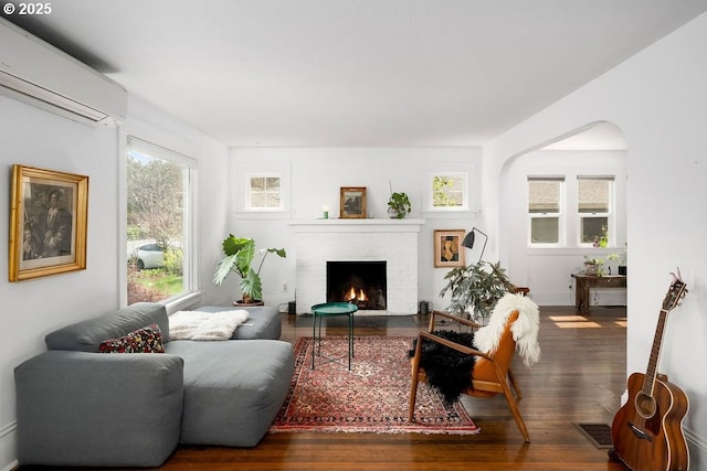 4541 NE 36th Ave, Portland, OR 97211 - living room featuring an AC wall unit, hardwood / wood-style floors, a brick fireplace, and arched walkways