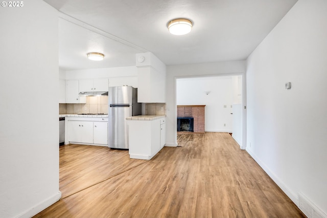 2210 Winter St SE, Salem, OR 97302 - kitchen with appliances with stainless steel finishes, tile countertops, light wood-style floors, white cabinets, and under cabinet range hood