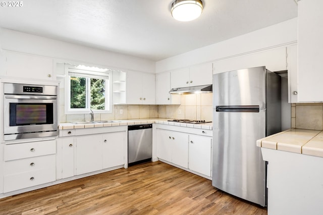 2210 Winter St SE, Salem, OR 97302 - kitchen featuring stainless steel appliances, tile countertops, backsplash, and white cabinetry