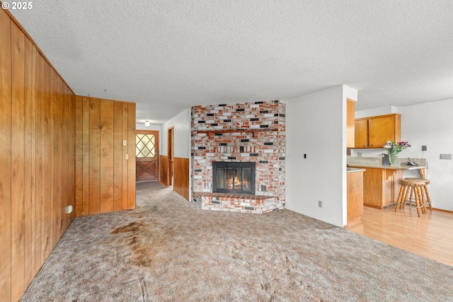 1223 Sable Dr, Roseburg, OR 97470 - unfurnished living room featuring a textured ceiling, wood walls, carpet, and a brick fireplace