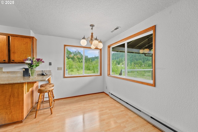 1223 Sable Dr, Roseburg, OR 97470 - dining space with a baseboard heating unit, a chandelier, light wood-type flooring, a textured ceiling, and baseboards