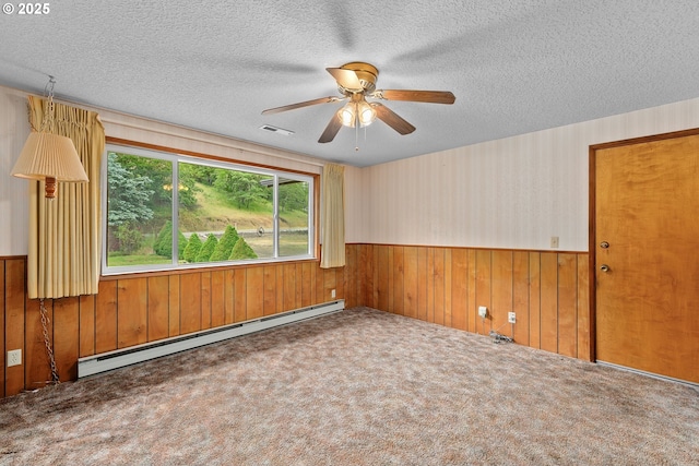 1223 Sable Dr, Roseburg, OR 97470 - carpeted empty room with baseboard heating, wood walls, a wainscoted wall, a textured ceiling, and ceiling fan