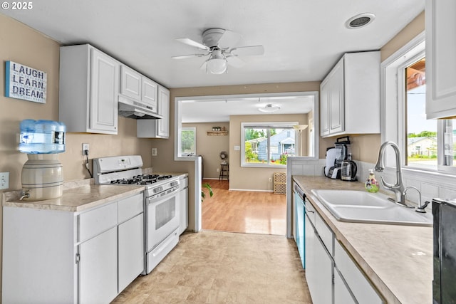 730 23rd St, Springfield, OR 97477 - kitchen with white gas stove, under cabinet range hood, a ceiling fan, and white cabinets