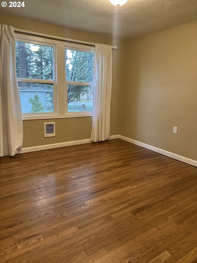 empty room with plenty of natural light and dark wood-type flooring