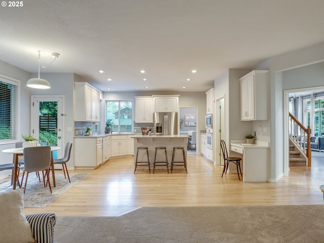 1354 Skye Pkwy, West Linn, OR 97068 - kitchen with stainless steel appliances, plenty of natural light, a kitchen bar, white cabinets, and recessed lighting
