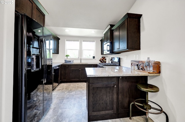 2057 S 59th St, Springfield, OR 97478 - kitchen featuring black appliances, a peninsula, dark brown cabinetry, light stone countertops, and recessed lighting