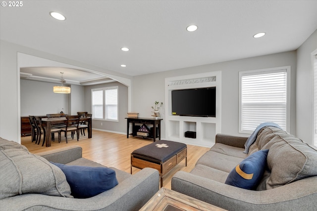 living area featuring light wood-type flooring, baseboards, arched walkways, and recessed lighting