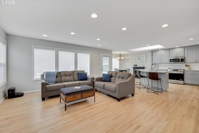 living area featuring light wood-type flooring, a notable chandelier, baseboards, and recessed lighting