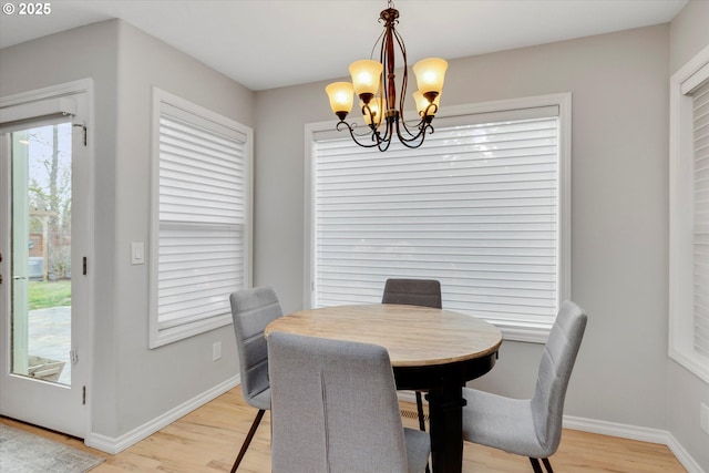 dining room featuring a chandelier, light wood finished floors, and baseboards