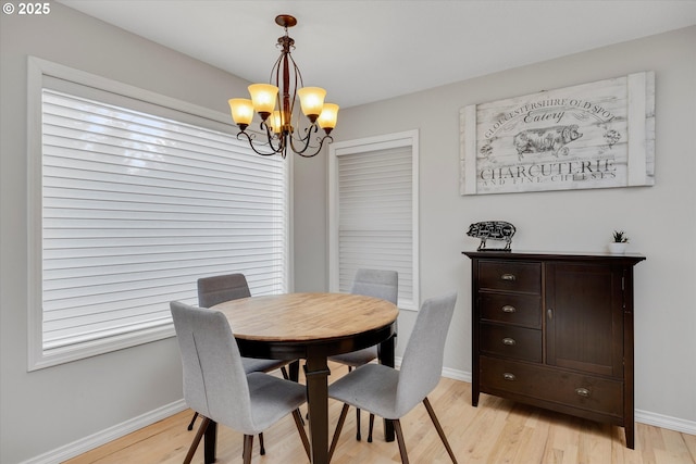 dining room featuring baseboards, light wood-style floors, and a notable chandelier