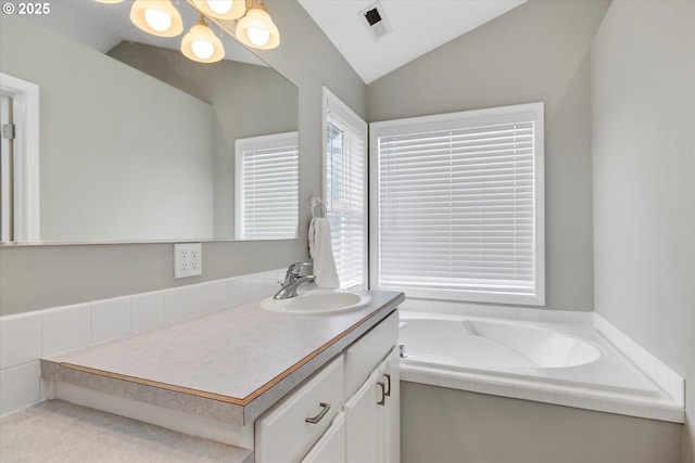 full bathroom featuring visible vents, vaulted ceiling, a bath, and vanity